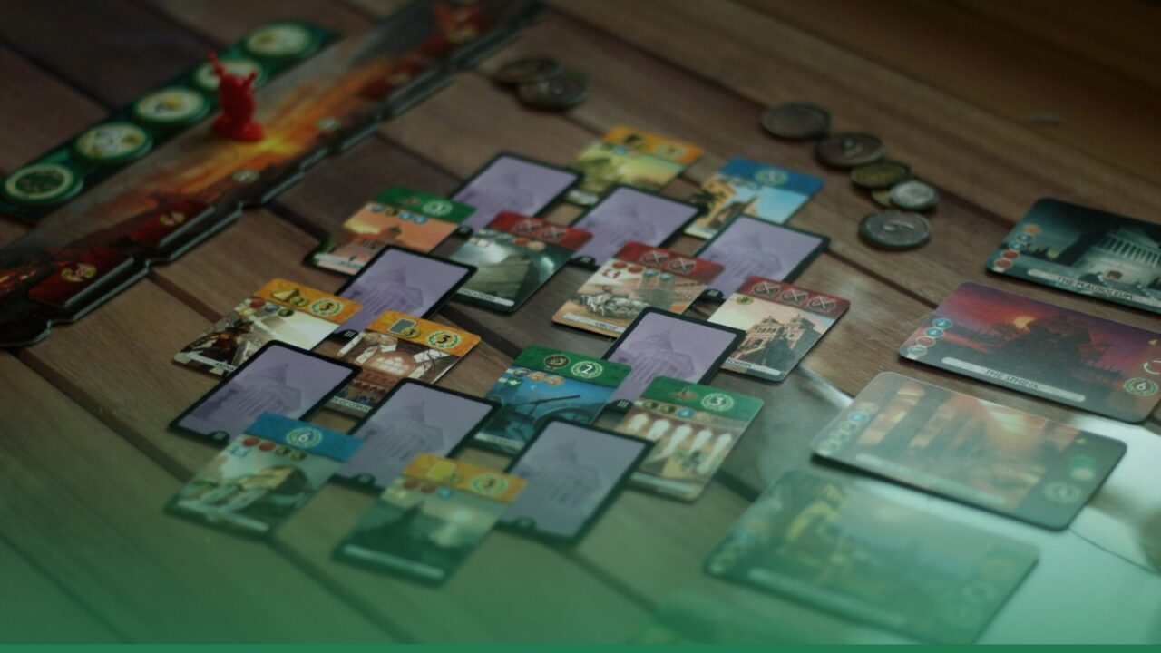A board game in progress with cards and tiles spread across the table